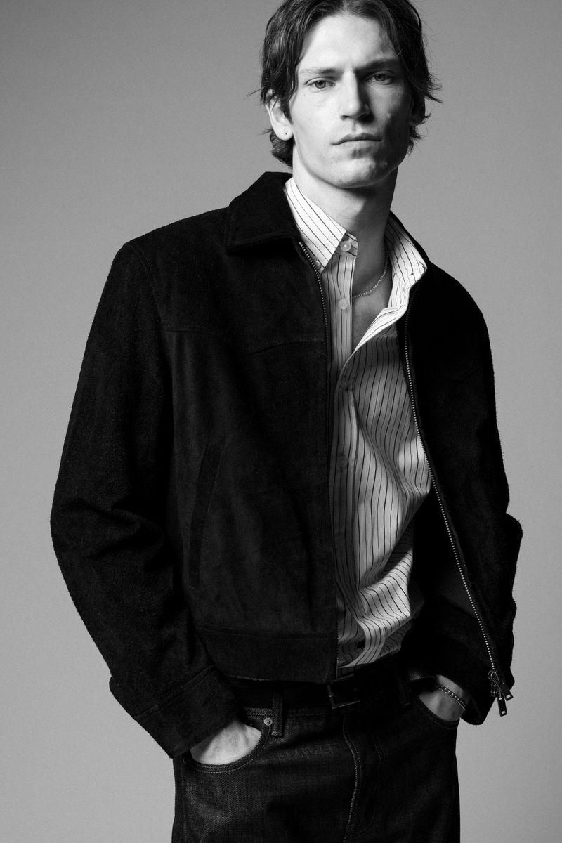 Model Justin Eric Martin wearing an open black jacket and striped shirt for Zara 90s Archive.