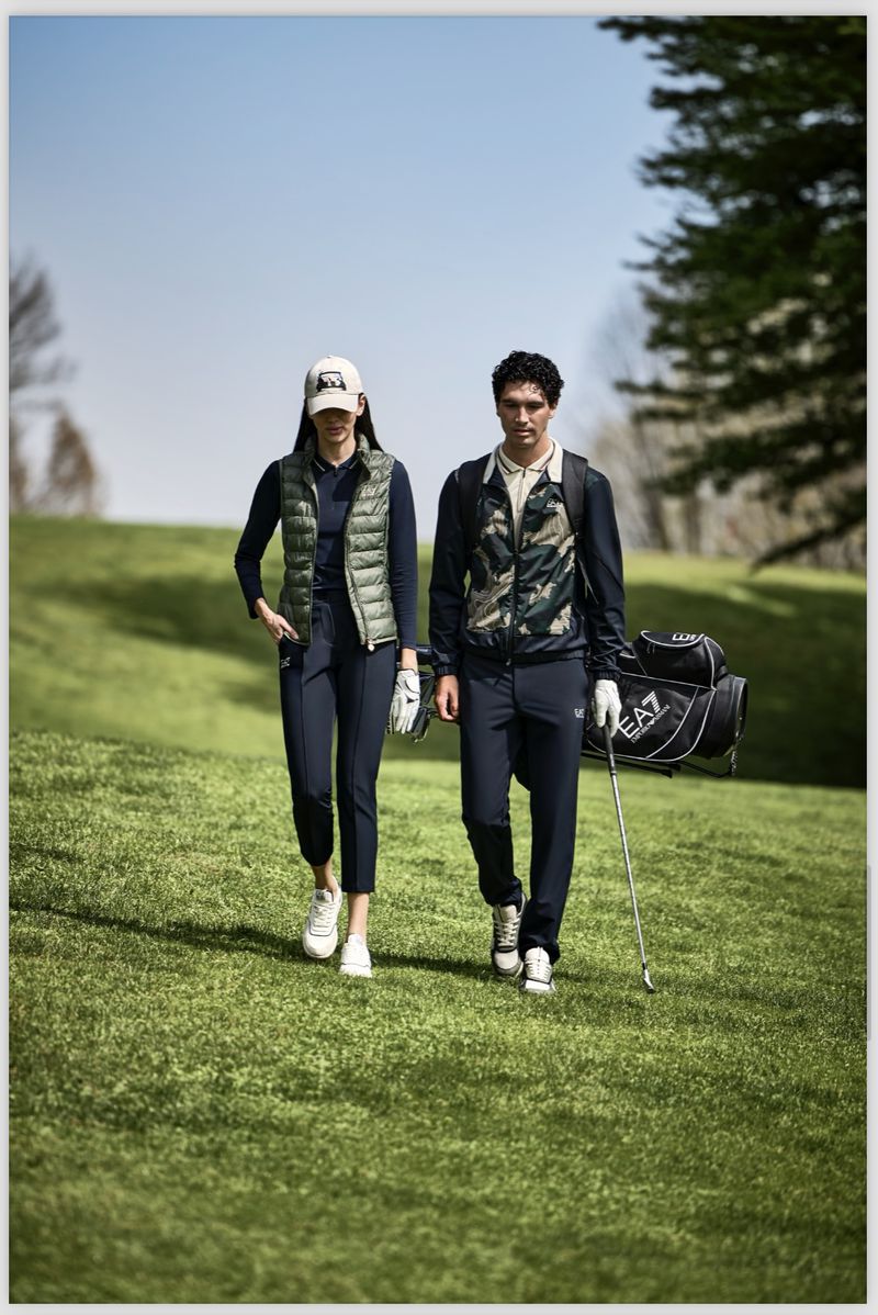 Two golfers, male and female, walk a green fairway in sporty attire with golf bag and club, enjoying a sunny day on the course.