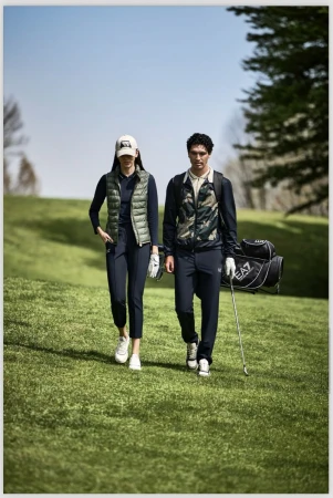 Two golfers, male and female, walk a green fairway in sporty attire with golf bag and club, enjoying a sunny day on the course.