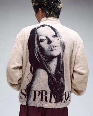 Person seen from behind wearing an off-white fleece jacket featuring a large black portrait graphic and Supreme branding on the back.