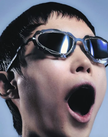 Close-up of an Asian woman with her mouth open wearing metallic sunglasses, shot in front of a light blue background.
