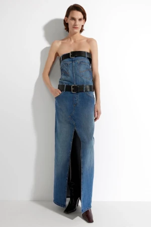 Woman in strapless denim dress with belts, full shot in a bright white studio.  Fashion editorial image with a modern, edgy aesthetic.