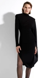 Model wearing a black mock neck dress with a draped sleeve against a plain white studio background.
