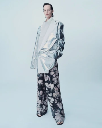Model Sara Blomqvist in an oversized metallic silver blazer and floral wide-leg trousers against a light backdrop.