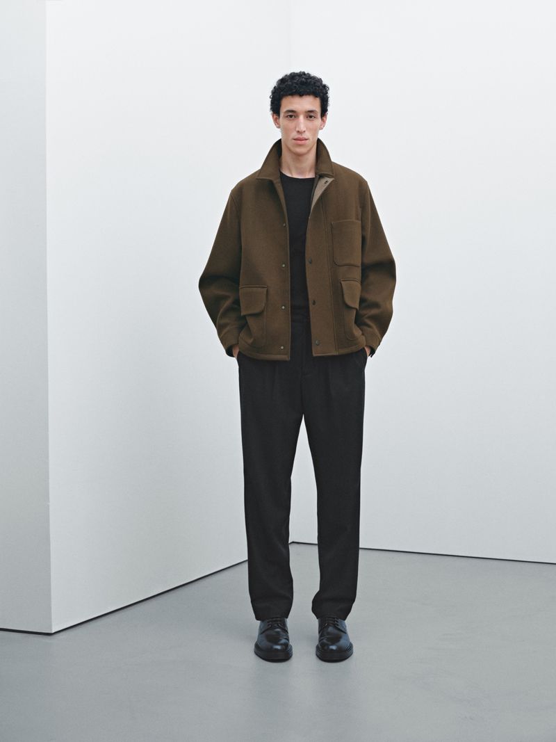 Model Walid Fiher wearing an olive brown wool utility jacket and black trousers for Massimo Dutti against a white studio wall