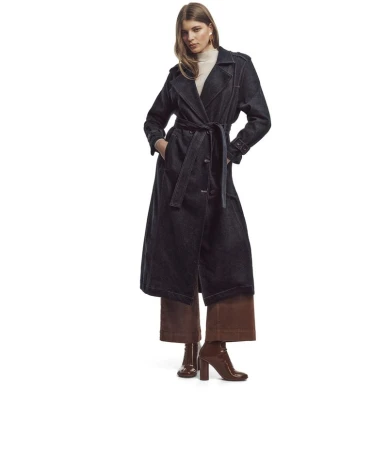 Model Mirthe Dijk wearing a dark denim belted trench coat and brown wide-leg trousers against a white seamless background.