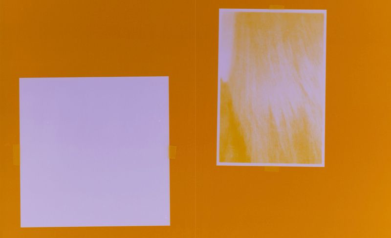 Orange backdrop featuring two white rectangular objects, one square and one vertically oriented, both affixed with clear tape.