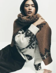 Model wearing a patterned knit sweater and brown scarf against a plain white studio background for Bloomingdale's.