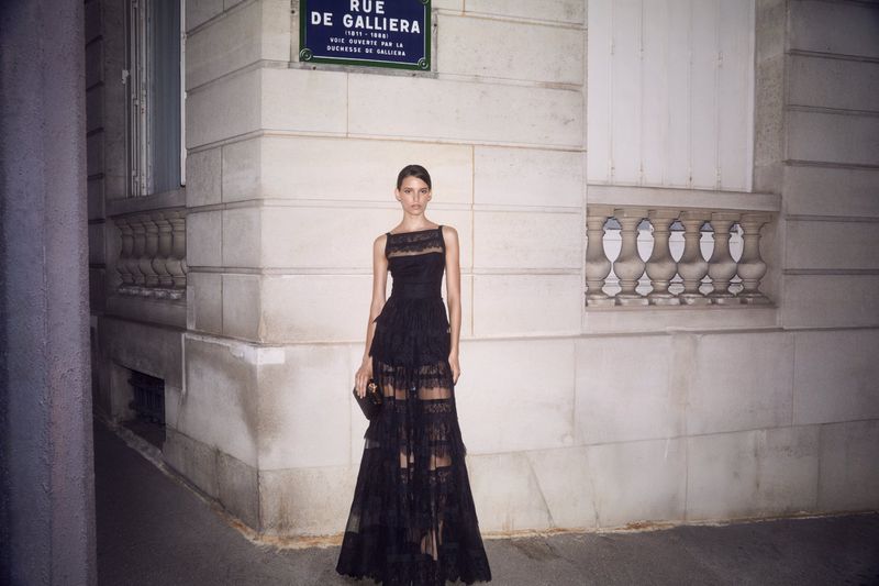 A woman in a black formal dress poses in front of a building on Rue de Gailliera, illuminated by soft, indirect light.