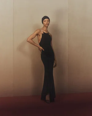 Model wearing a black evening dress and cap standing against a neutral background for Zara