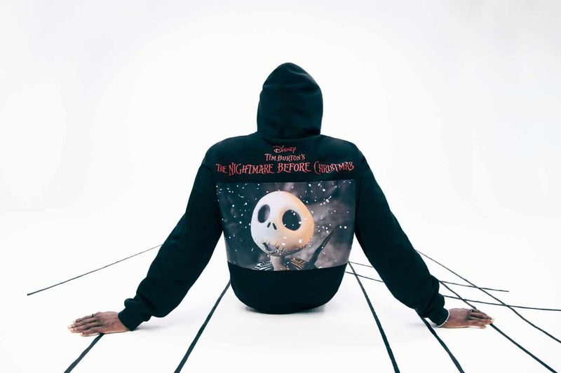 Back view of person wearing a black hoodie with 'The Nightmare Before Christmas' graphic, standing against a white background with black lines.