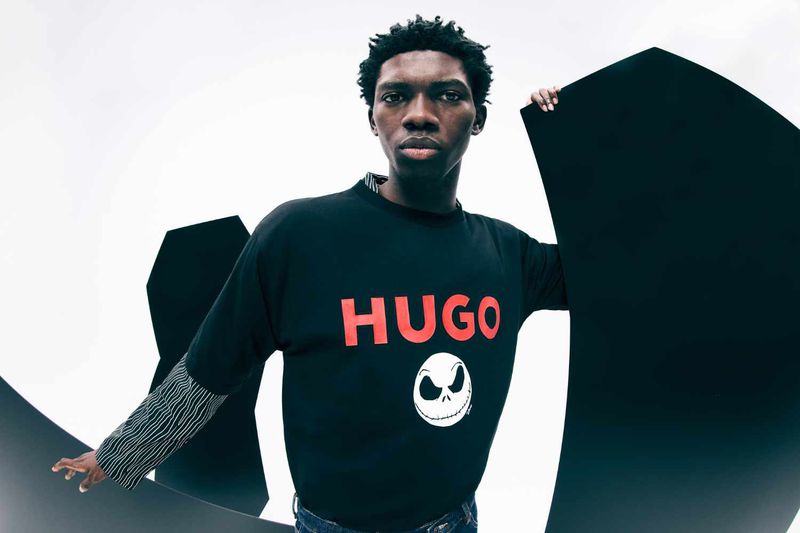 Man in HUGO sweater with Jack Skellington graphic posing with black shapes on a white background in a fashion studio shot.