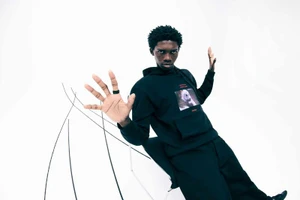 Model Ottawa Kwami wearing a black hoodie with graphic print in a studio setting for Hugo x Nightmare before Christmas.