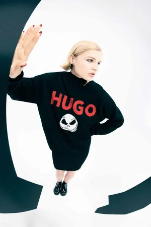 Model in black HUGO sweater with graphic print posing against white background