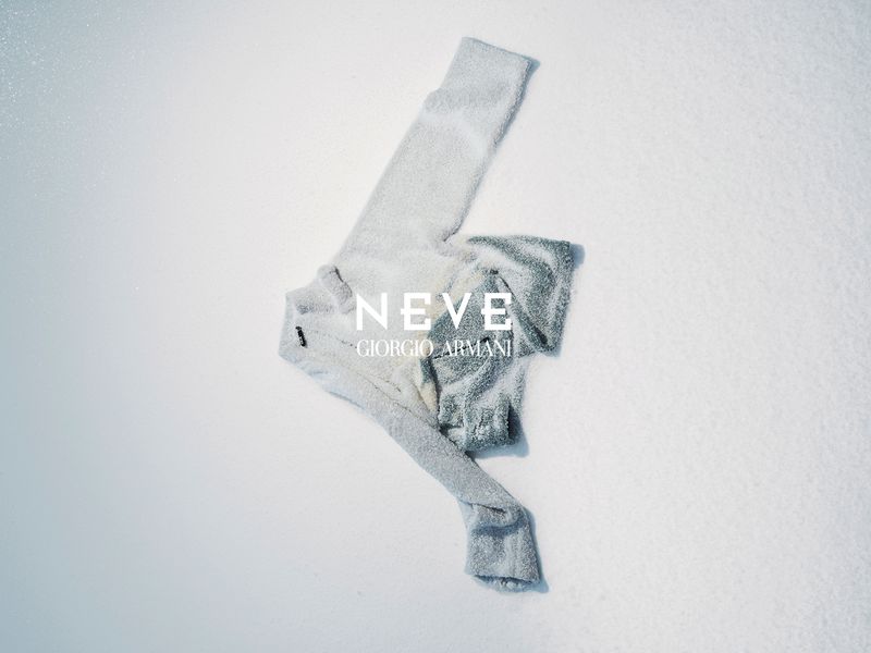 Elevated view of a neatly arranged grey Giorgio Armani wool tracksuit on a snowy surface with the brand's text logo visible.