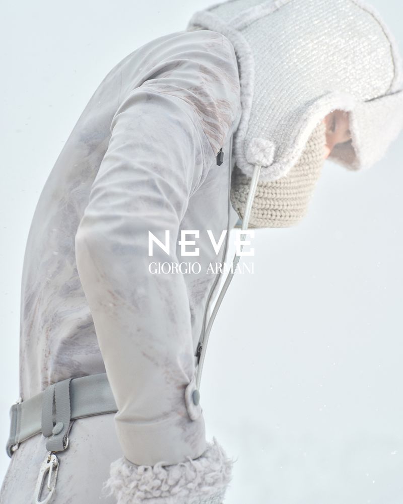 Fashion shot of a model wearing a white winter coat and hat, posing against a bright white background, in a studio setting, for an ad.