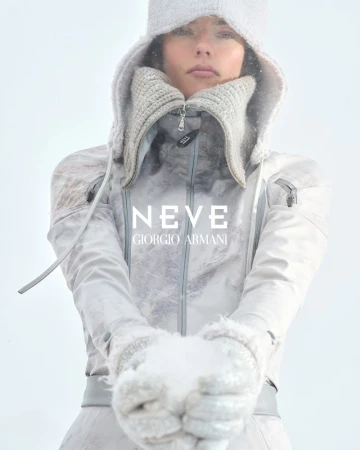 Fashion shot featuring a model in a winter hooded outfit, holding snow in her hands, against a bright background in a winter fashion theme.