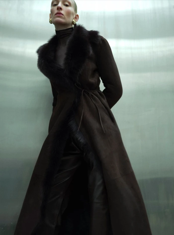 Model Maggie Maurer wearing a dark brown fur-trim coat for Nour Hammour Fall 2024 campaign