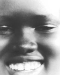 Close-up monochrome portrait of a smiling person showing teeth, captured with a soft blur and high-contrast light.