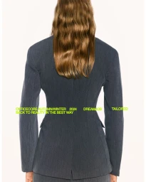 Rear view of a woman with long wavy brown hair wearing a grey tailored blazer against a clean white background