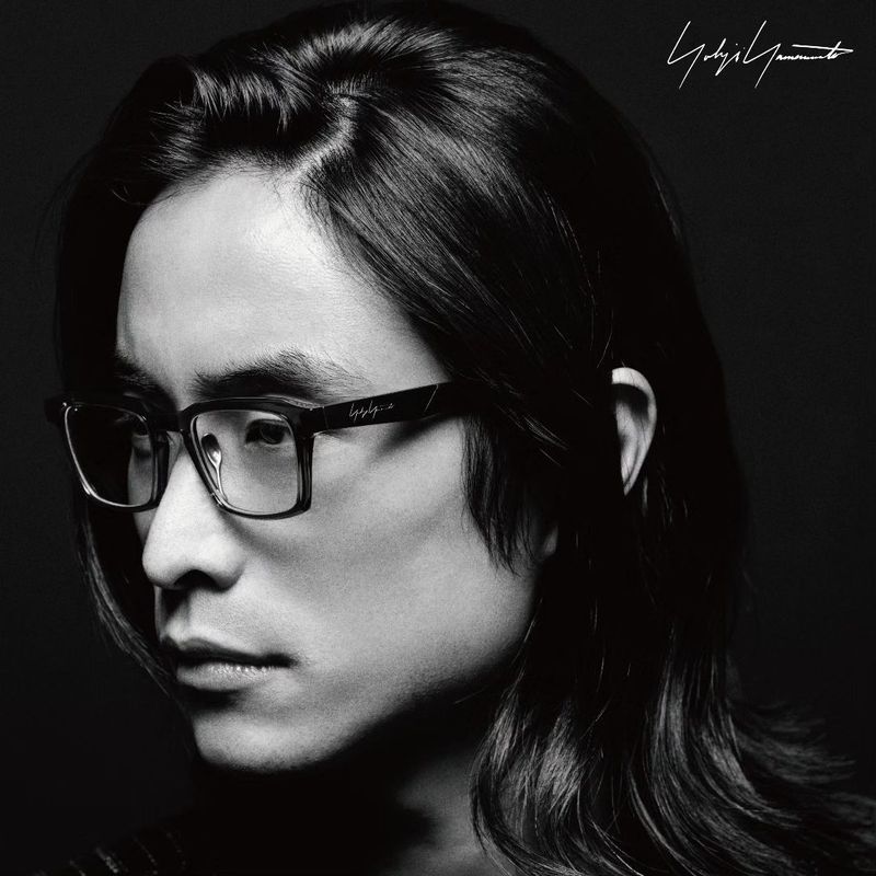 Portrait of an adult male wearing glasses in a close-up shot. The image is black and white with the man facing the camera.