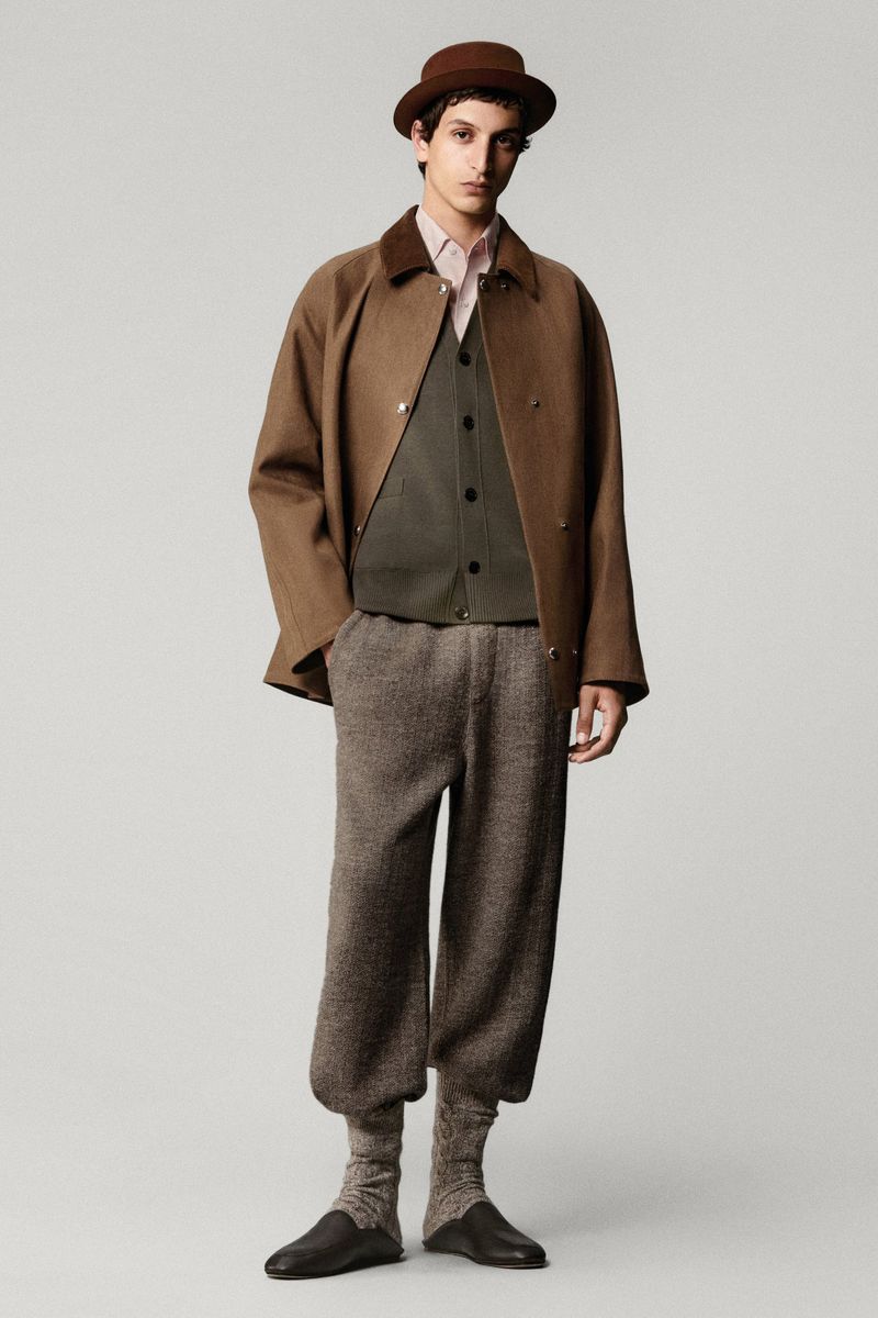 Full-length studio shot of a man wearing a brown bowler hat, coat, vest, shirt, trousers, socks, and shoes, standing against a neutral background.