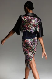 Model seen from behind wearing a floral patterned skirt and jacket with black leather collar