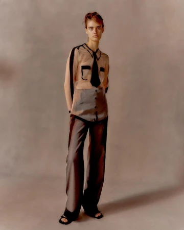 Model Becky Skirrow wearing a sheer shirt with trompe l'oeil black tie detailing and matching sheer trousers for Steve O Smith.
