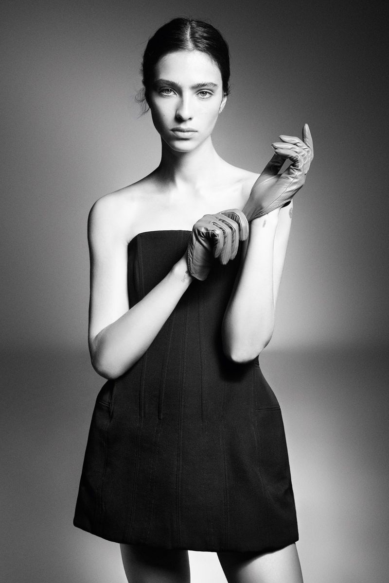 Elegant portrait of a slender woman in a black dress and gloves, showcasing fashion and portrait photography in a photo studio.