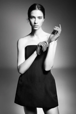 Elegant portrait of a slender woman in a black dress and gloves, showcasing fashion and portrait photography in a photo studio.