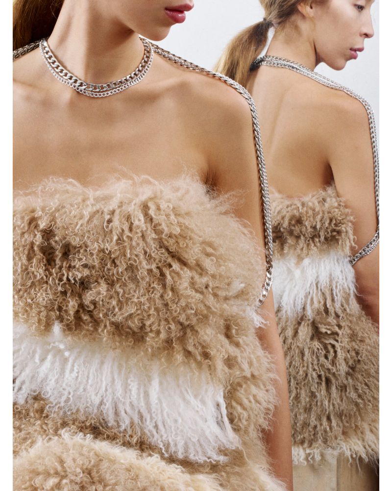 Fashion shot of a woman wearing a fluffy strapless top and silver chain necklace, showcasing fashion and textile design.