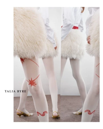 Fashion shot showcasing a woman's legs with white tights, gold heels, and a fluffy white skirt, featuring red star and snake designs.
