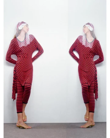 Two adult females mirroring in a studio portrait, wearing a red and black striped dress, sheer white floral bonnet, and gold kitten heels.
