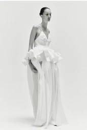 Model in white ruffled dress against a light background for Ashlyn S/S25
