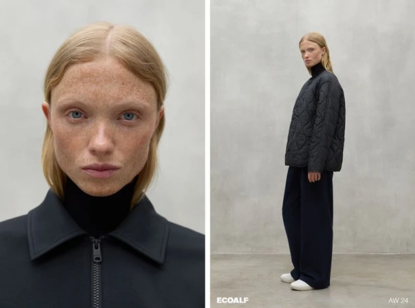Fashion shot of a blonde woman wearing a quilted jacket and navy wide-leg trousers, posing in front of a neutral background.