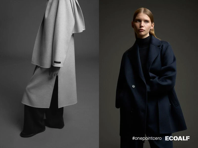 Fashion editorial shot against grey backdrop featuring an adult woman in a navy coat and a grey coat. Minimalist clothing in a studio.