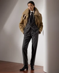Model Amane Taniguchi wearing a tailored charcoal suit and a tan shearling jacket for Ralph Lauren Collection Pre-Fall 2024.