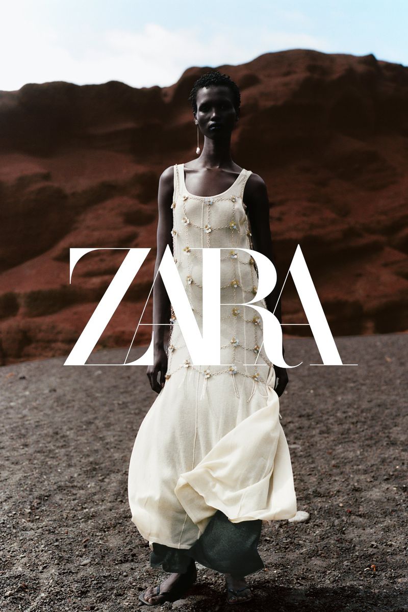 Model Amar Akway in a cream draped dress standing against a volcanic red rock landscape for the Zara Vulcano campaign.
