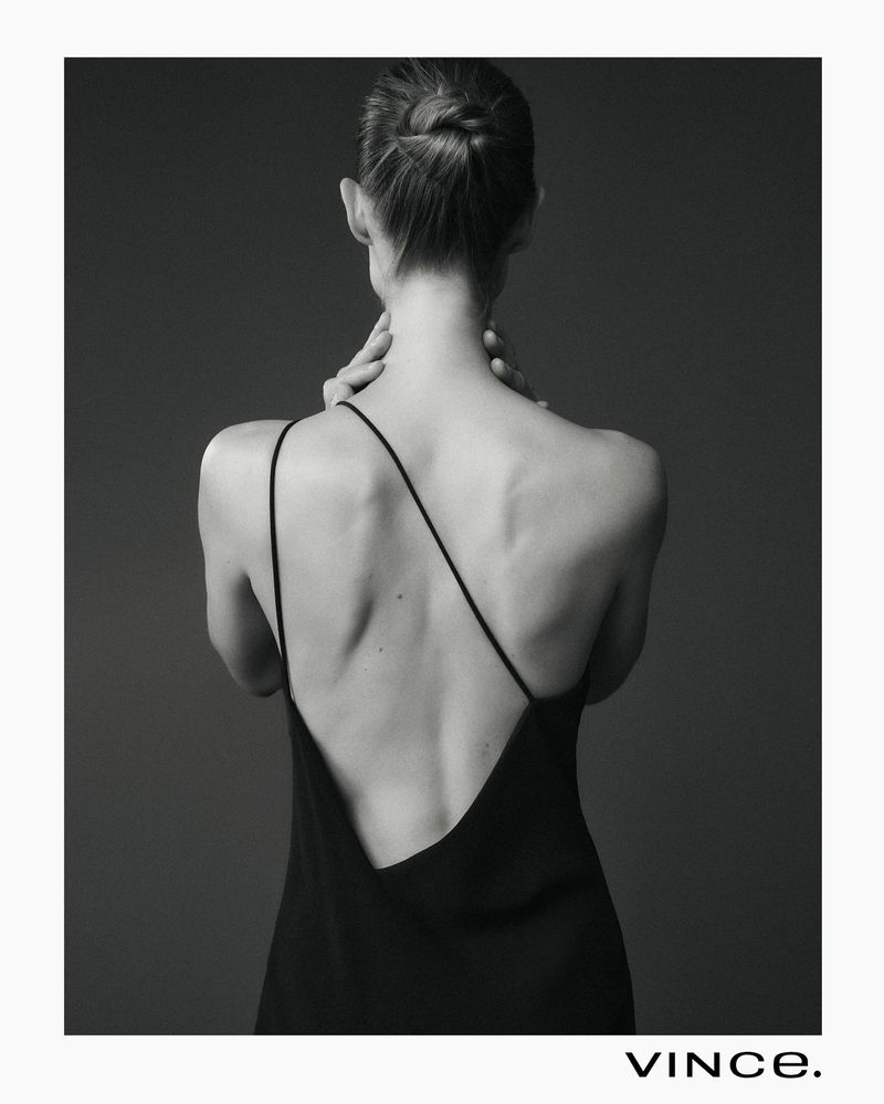 Woman posing with bare back in elegant black dress in a studio with neutral background and clean, modern style. Fashion photography.