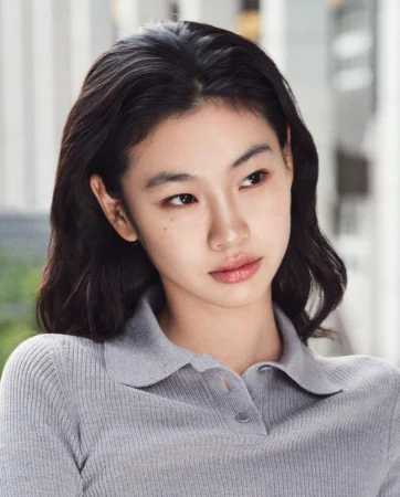Headshot of an Asian woman with dark hair in a grey collared top, looking slightly away from the camera in an outdoor setting.