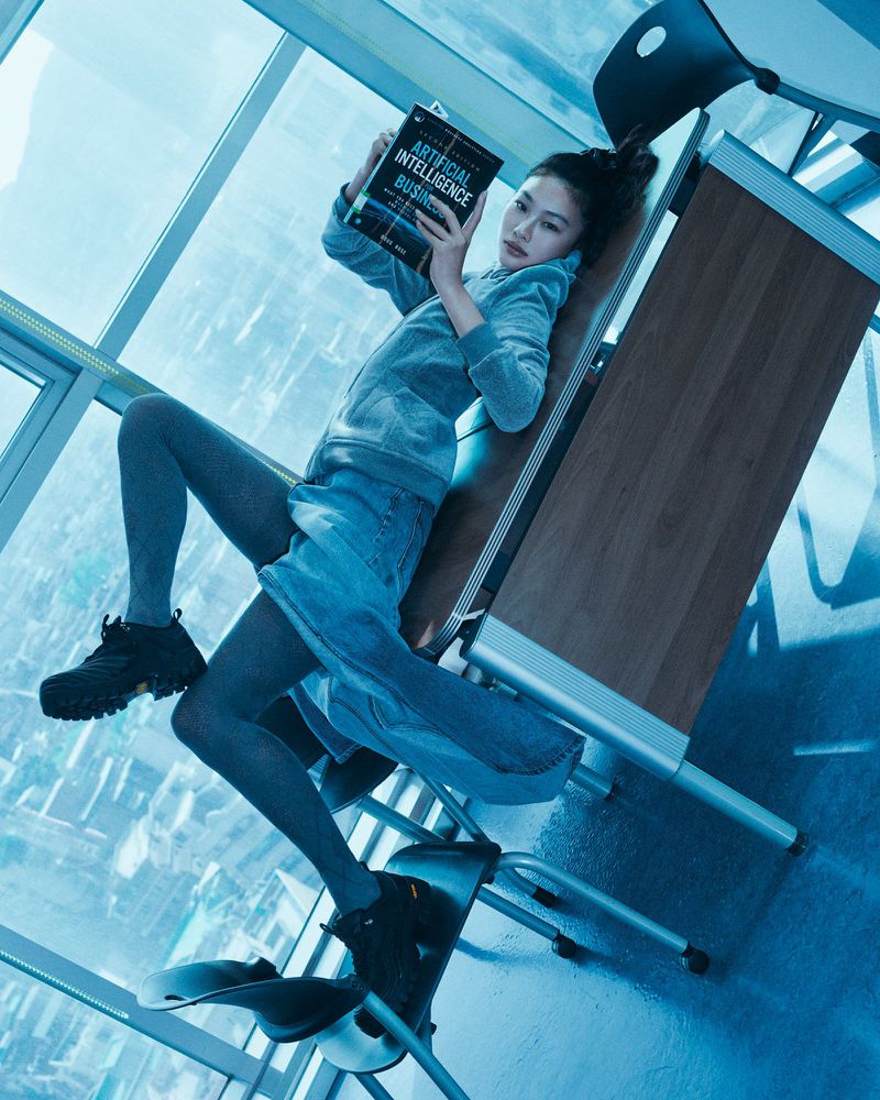 Adult female laying on desk, reading AI Artificial Intelligence Business book in modern blue indoor environment with futuristic setting.