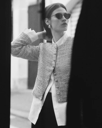Monochrome fashion portrait of a model in sunglasses and a textured tweed jacket outdoors