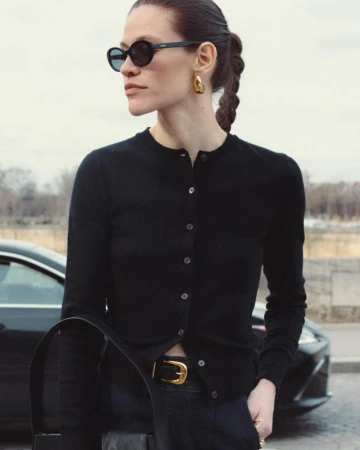 Model wearing dark sunglasses and a black cardigan standing outdoors near a car for Derek Lam 10 Crosby Fall 2024