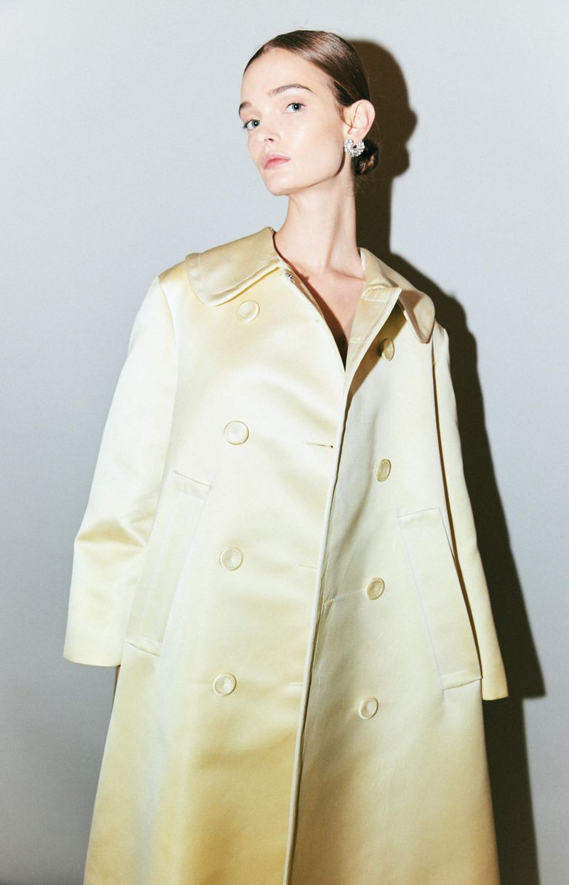 Model Lulu Tenney wears a pale butter yellow satin double-breasted coat for the Altuzarra SS24 collection.