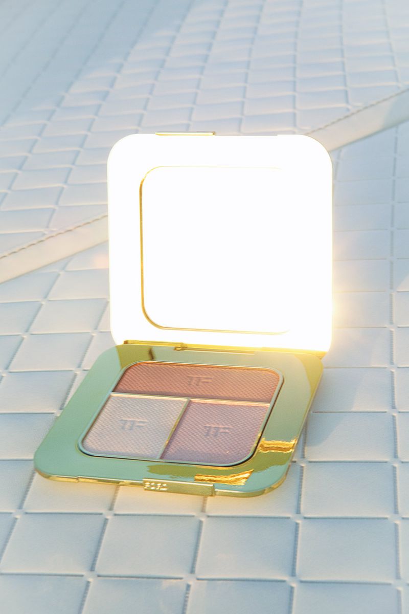 Tom Ford eyeshadow palette on a white tiled surface with gold accents, showcasing a makeup product in a beauty setting.