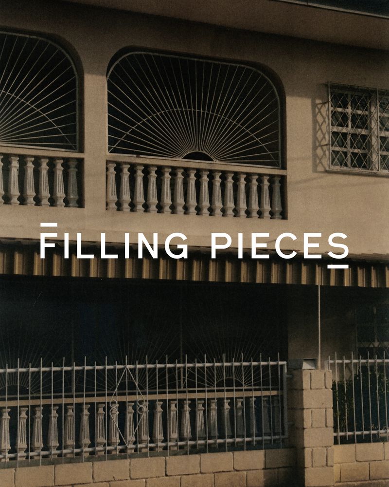 Exterior of a building with a decorative balcony and windows, featuring a fence and the text 'FILLING PIECES' overlaid.