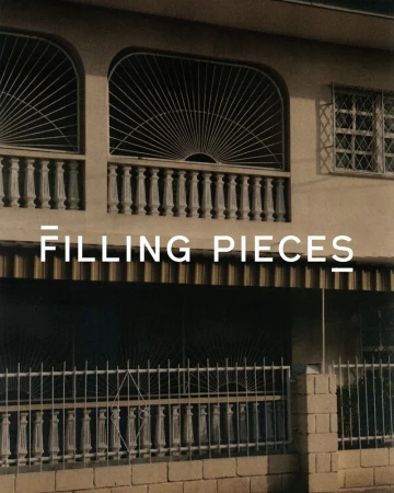 Exterior of a building with a decorative balcony and windows, featuring a fence and the text 'FILLING PIECES' overlaid.