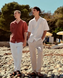 Two male models standing on a rocky beach wearing short sleeve button-down shirts and light trousers for Lefties Summer Collection.
