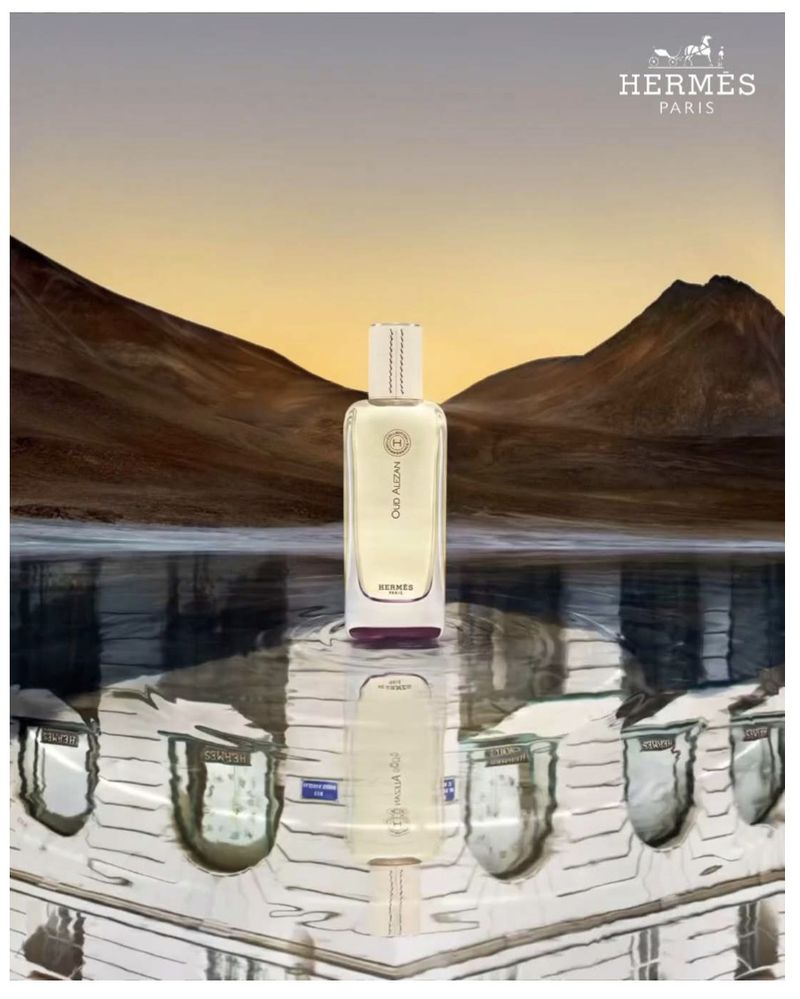 Hermès Oud Alezan perfume bottle stands out with a mountain backdrop, mirrored base, and elegant Hermès branding, creating a luxurious feel.