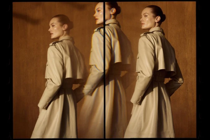 A woman in a tan trench coat poses in a studio, viewed from the side with a blurred triple exposure effect. Fashionable studio shot.
